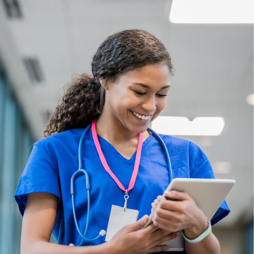 healthworker using tablet cropped square woman wearing bright blue scrubs wears an id lanyard and stethoscope while looking at a tablet